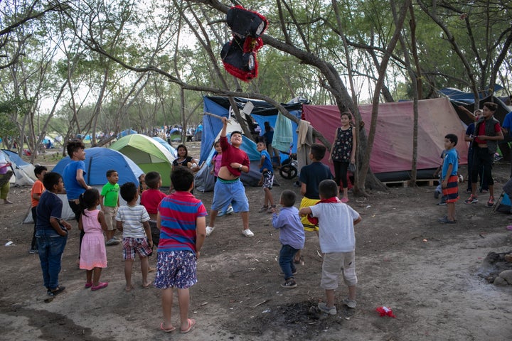 Immigrant children break a birthday pinata at a camp for asylum-seekers on Dec. 9, 2019, in Matamoros.