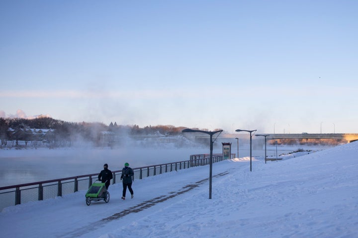 Pedestrians walk by River Landing on the South Saskatchewan River during an extreme cold warning in Saskatoon, Sask. on Feb. 5, 2021.