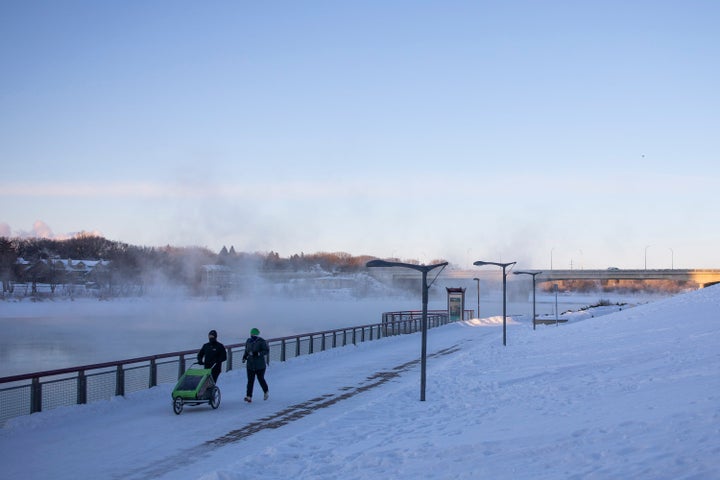 Pedestrians walk by River Landing on the South Saskatchewan River during an extreme cold warning in Saskatoon, Sask. on Feb. 5, 2021. 