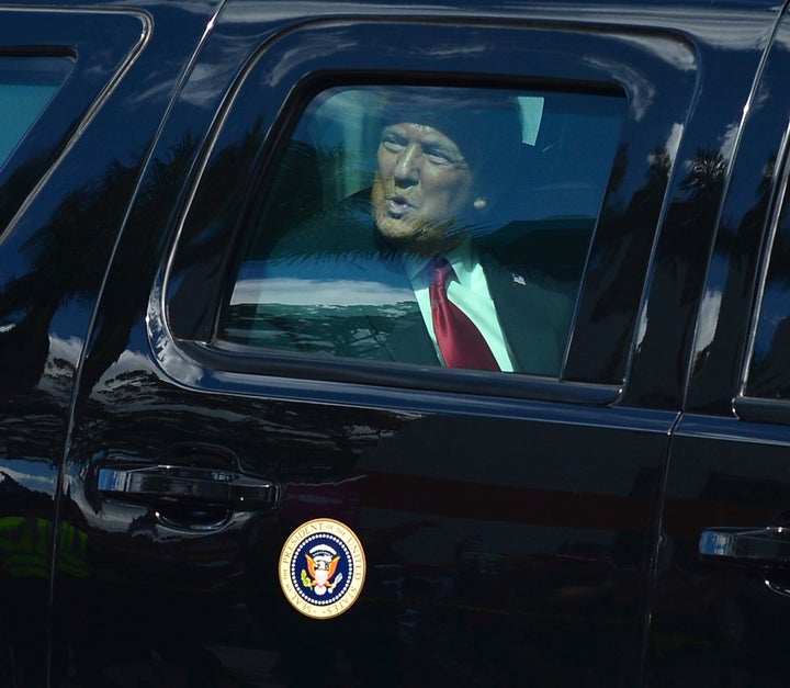 Donald Trump waves to supporters from his presidential motorcade after landing at Palm Beach International Airport on the way