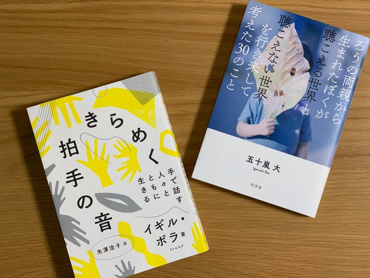 （左から）イギル・ボラさんの翻訳書『きらめく拍手の音』（リトルモア）、CODAについて書いた筆者の新刊『ろうの両親から生まれたぼくが聴こえる世界と聴こえない世界を行き来して考えた30のこと』（幻冬舎）