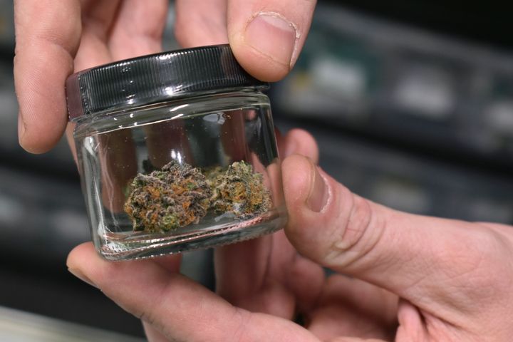A worker holds up a jar with marijuana offered for sale at Montana Advanced Caregivers, a medical marijuana dispensary, in Billings, Mont. Recreational marijuana initiatives passed in four states last year year, from liberal New Jersey to conservative Montana and South Dakota.