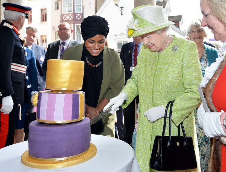 Queen Elizabeth II cuts into a birthday cake baked by Nadiya Hussain, left, during the queen's 90th birthday celebration in Windsor, England, on April 21, 2016.