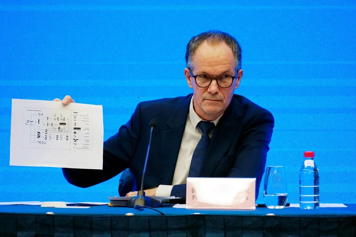 Peter Ben Embarek, a member of the WHO team tasked with investigating the origins of COVID-19, holds up a document Tuesday in Wuhan, China.