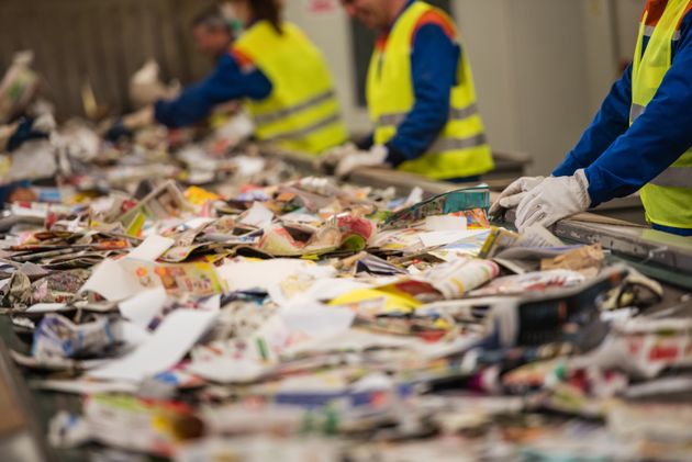 Workers sorting papers on factory assembly line for recycling at recycling