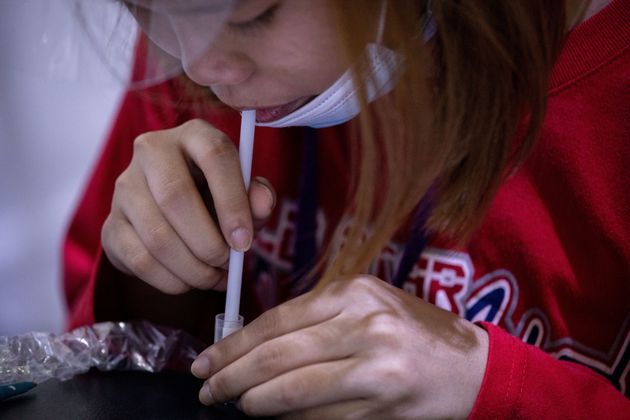 Une femme aux Philippines réalise un test salivaire pour le Covid-19.