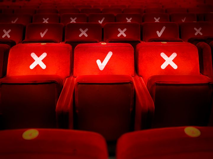 rows of empty chairs in a theater with the indication of where it is possible to sit to maintain the social safety distance during the period of the COVID-19 corona virus pandemic. Social distancing