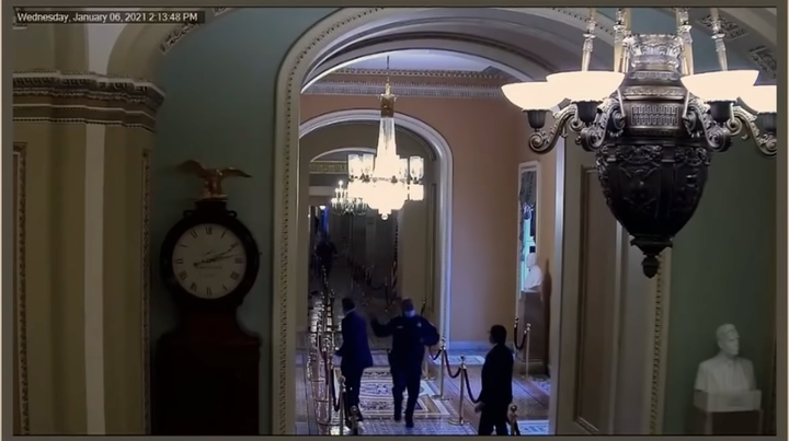 Sen. Mitt Romney (left) and U.S. Capitol Police Officer Eugene Goodman seen in security camera video during the Jan. 6 attack.