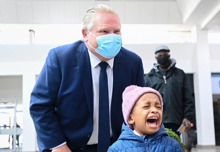 Two year-old Sanaa-Marie Best cries as Ontario Premier Doug Ford poses for a photograph as he tours the Wellfort Community Health Services in Mississauga, Ont., on Feb. 9, 2021.