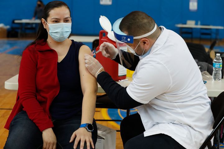 A Peter Cooper Public School teacher receives the Moderna coronavirus vaccine from a Walgreens pharmacist at Roberto Clemente Community Academy of Chicago on Feb. 11, 2021.