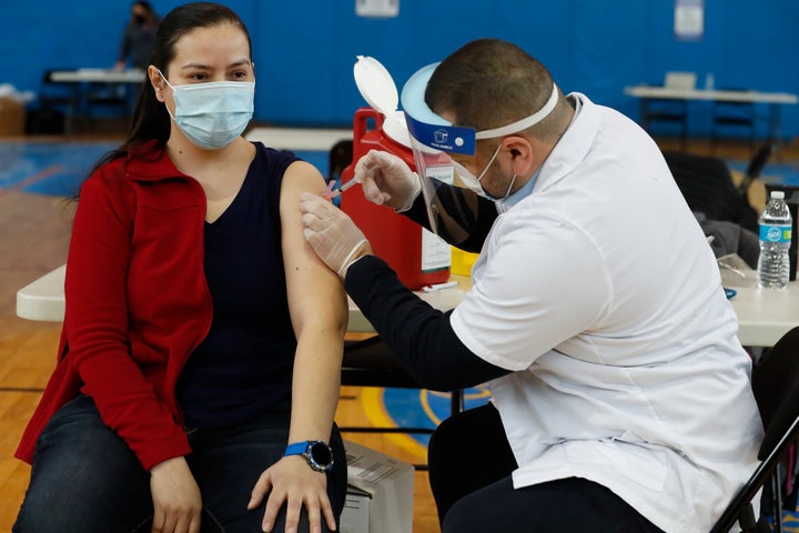 A Peter Cooper Public School teacher receives the Moderna coronavirus vaccine from a Walgreens pharmacist at Roberto Clemente Community Academy of Chicago on Feb. 11, 2021.