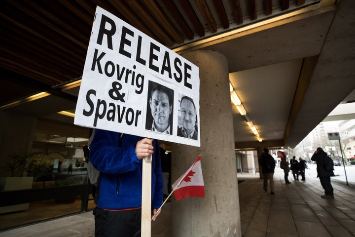 A young man holds a sign bearing photographs of Michael Kovrig and Michael Spavor on Jan. 21, 2020.