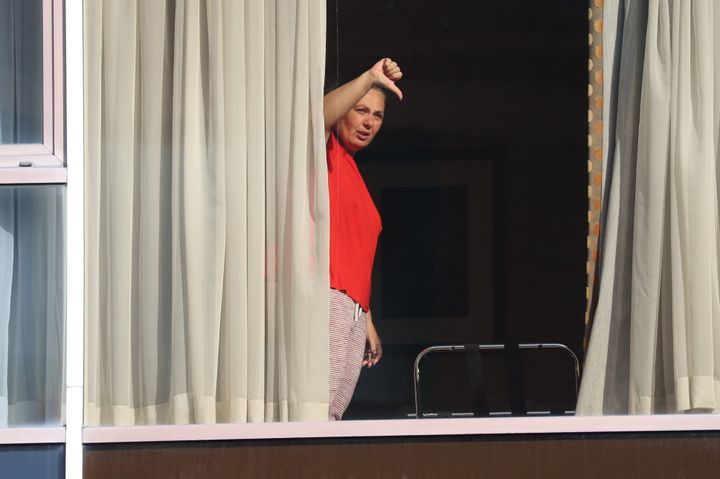 <strong>Andressa Pelosini, 43, who is with Roger Goncalves from Brazil, gestures to members of the media from the window of Radisson Blu Edwardian Hotel, near Heathrow Airport.</strong>
