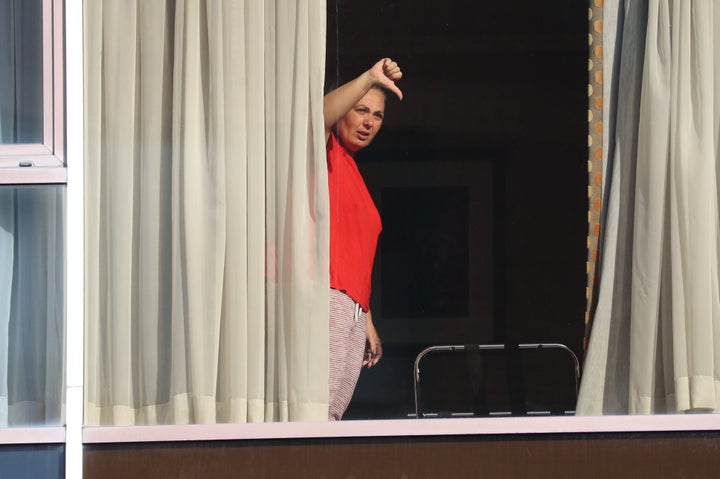 Andressa Pelosini, 43, who is with Roger Goncalves from Brazil, gestures to members of the media from the window of Radisson Blu Edwardian Hotel, near Heathrow Airport.