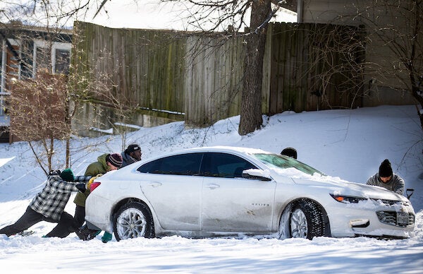 East Austin residents push a car out of the snow on Monday.