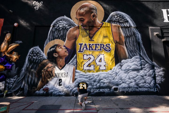 Un homme rend hommage à Kobe Bryant et à sa fille Gianna, devant une peinture murale de l’artiste Louie Sloe Palsino, le 26 janvier 2021, à Los Angeles, un an après leur mort dans un accident d’hélicoptère.