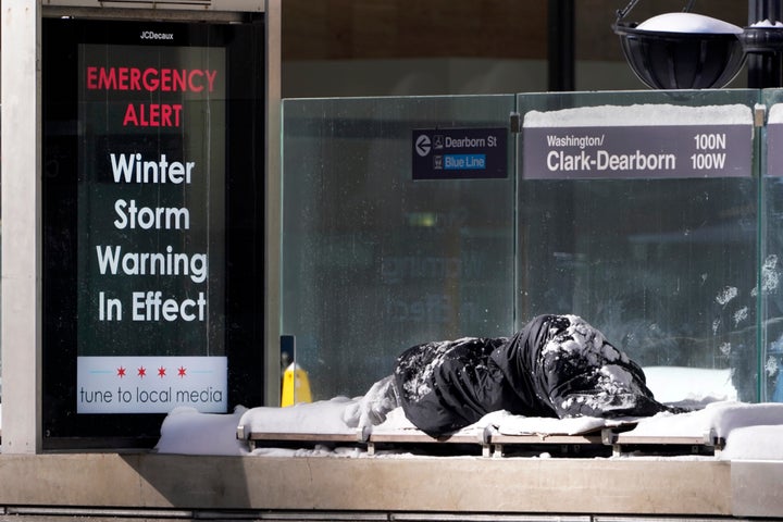 A homeless man Tuesday, Feb. 16, 2021, sleeps at the Chicago Transit Authority's Clark & Dearborn bus station, the morning after a snowstorm dumped up to 18 inches in the greater Chicago area. (AP Photo/Charles Rex Arbogast)