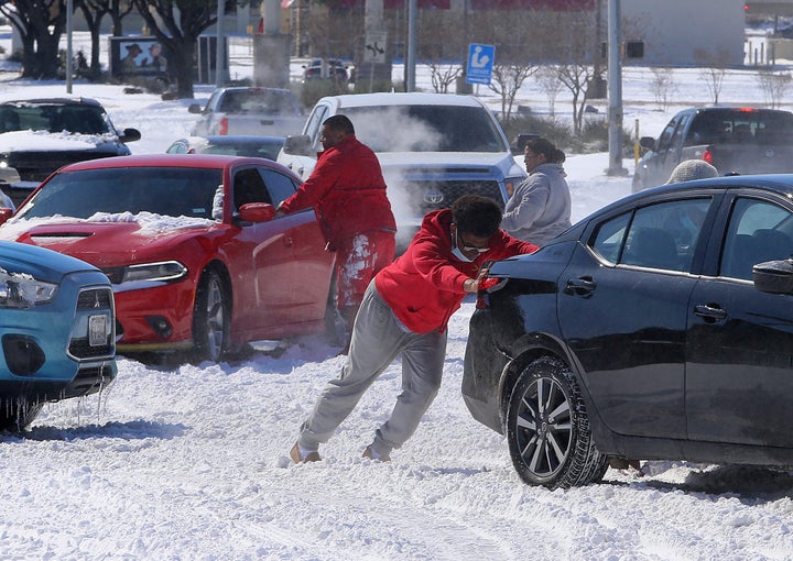 People push a car free after spinning out in the snow Monday, Feb. 15, 2021 in Waco, Texas. (Jerry Larson/Waco Tribune-Herald via AP)