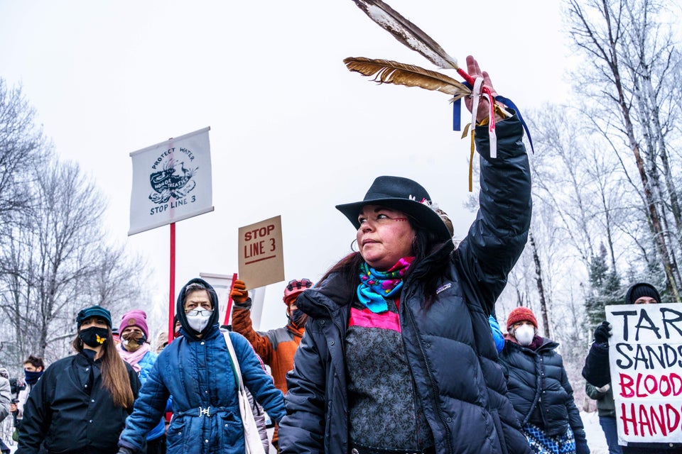 A Native American environmental activist dances with an eagle feather in front of the construction site...