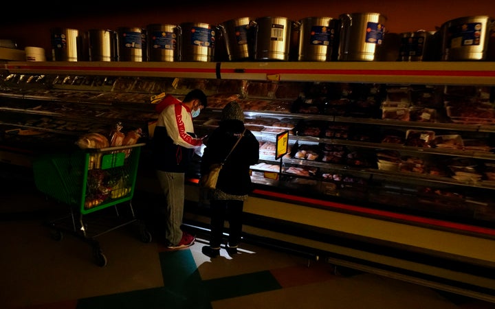 Customers use a cell phone light to look in the meat section of a Dallas grocery store on February 16.  Although the store l