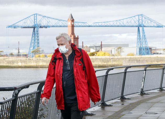 A man wearing a face mask walks by the Tees Transporter Bridge in Middlesbrough last October. 