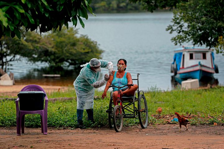 A health worker from the Ministry of Health Department for Indigenous Health adminsters a second doses of a COVID-19 vaccine to a woman in the village Esperanca do Rio Arapiun, in the Lower Amazon region of the state of Para, near Santarem in Brazil, on Feb. 14.