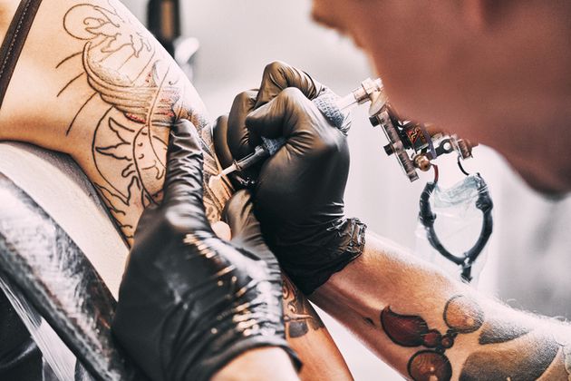 Artiste de tatouage faisant un tatouage sur une épaule (image d'illustration)