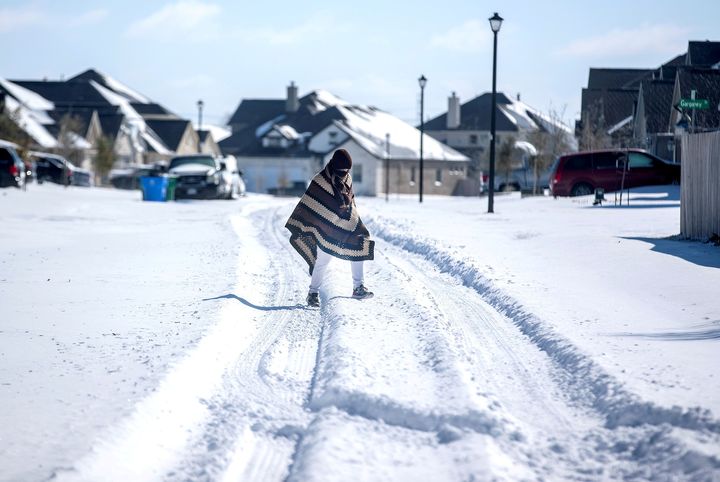 A man walks to his friend’s home in a neighborhood without electricity as snow covers the BlackHawk neighborhood in Pflugerville, Texas on Monday.