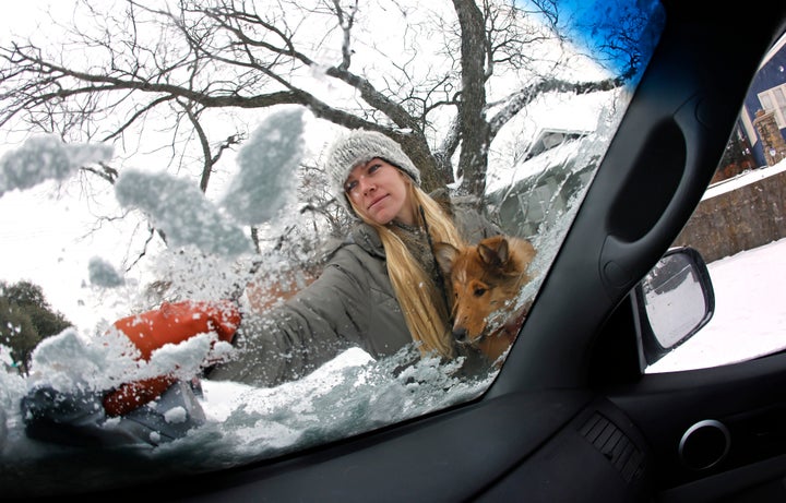 Caroline Marlett holds her dog Kit while scraping the snow off her car after a snow storm on Feb. 17 in Fort Worth, Texas.