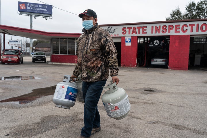 A person carries empty propane tanks, bringing them to refill at a propane gas station after winter weather caused electricity blackouts on Feb. 18 in Houston, Texas. Winter storm Uri brought severe temperature drops causing a catastrophic failure of the power grid in Texas.