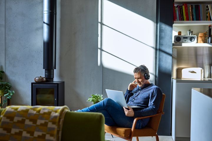 Mature man listening to music on laptop - stock photo