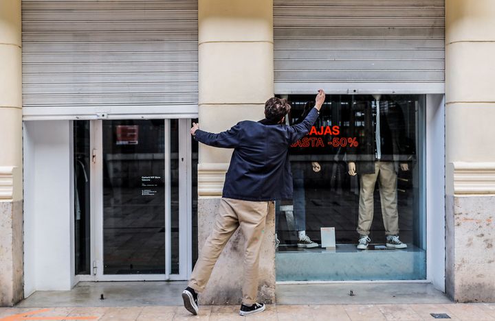 Un empleado cierra una tienda en Valencia a la hora del toque de queda.