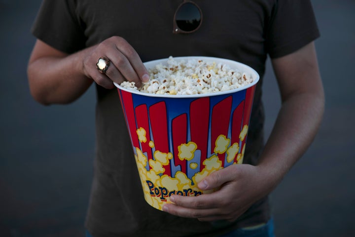 File photo of a moviegoer eats popcorn at Mission Tiki drive-in theater in Montclair, Calif. on May 28, 2020.