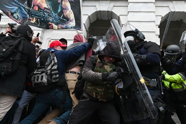 Riot police push back a crowd of supporters of then-President Donald Trump after they stormed the Capitol...