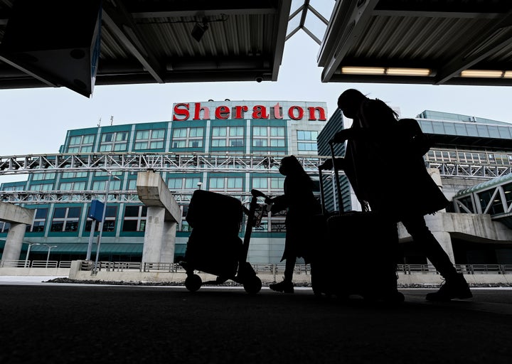 The airport hotel is shown as people walk outside with their luggage at Pearson International Airport during the COVID-19 pandemic in Toronto on Feb. 2, 2021.