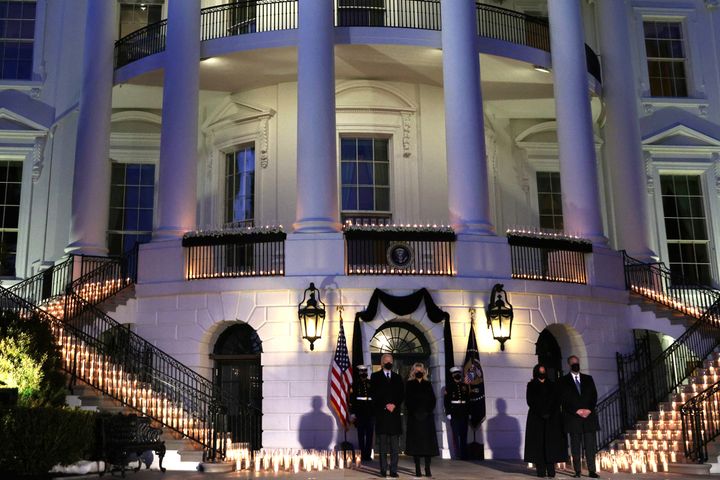 President Joe Biden, first lady Jill Biden, Vice President Kamala Harris and Harris's husband, Doug Emhoff, participate in a moment of silence at sundown Monday on the South Portico of the White House during a candlelight ceremony to mark the more than 500,000 lives lost in the U.S. to COVID-19.