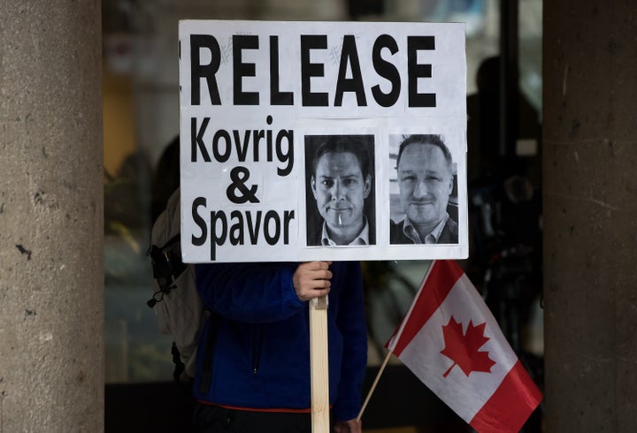 A young man holds a sign bearing photographs of Michael Kovrig and Michael Spavor outside B.C. Supreme Court where Huawei chief financial officer Meng Wanzhou was attending a hearing, in Vancouver on Jan. 21, 2020.