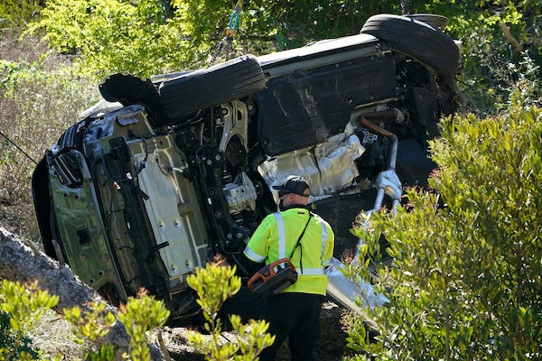 A law enforcement officer looks over a damaged vehicle following a rollover accident involving golfer Tiger Woods on Tuesday.