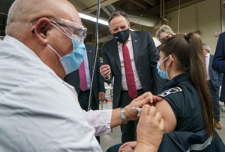 Quebec Premier Francois Legault watches a woman get her COVID-19 vaccine at a clinic in Montreal's Olympic Stadium on Feb. 23, 2021.