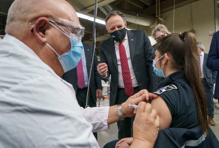 Quebec Premier Francois Legault watches a woman get her COVID-19 vaccine at a clinic in Montreal's Olympic Stadium on Feb. 23, 2021.