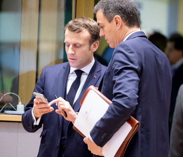 Emmanuel Macron et le premier ministre socialiste espagnol Pedro Sanchez discutent autour du téléphone du président français lors du sommet des dirigeants de l'Union européenne, le 13 décembre 2019 à Bruxelles, en Belgique. (Photo by Thierry Monasse/Getty Images)