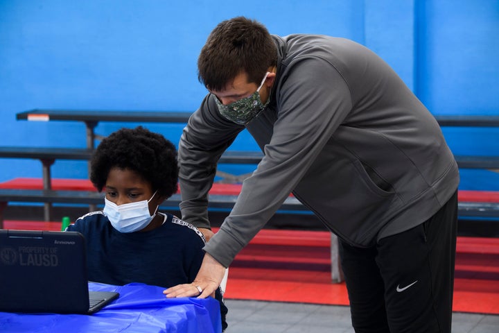 A staff member assists a child as they attend online classes at a learning hub inside the Crenshaw Family YMCA in Los Angeles on Feb. 17. The learning hub program provides distance-education resources while many area schools remain closed for in-person classes.