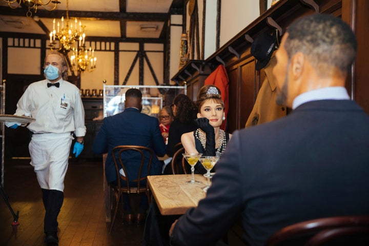 Wax statues of Audrey Hepburn and Michael Strahan occupy one of the tables at Peter Luger Steakhouse.