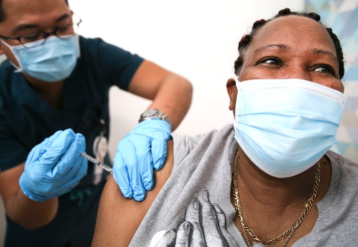 Lorraine Harvey, an in-home care worker, receives her first dose of the COVID-19 vaccine from registered nurse Rudolfo Garcia in South Los Angeles on Feb. 25, 2021 in Los Angeles.