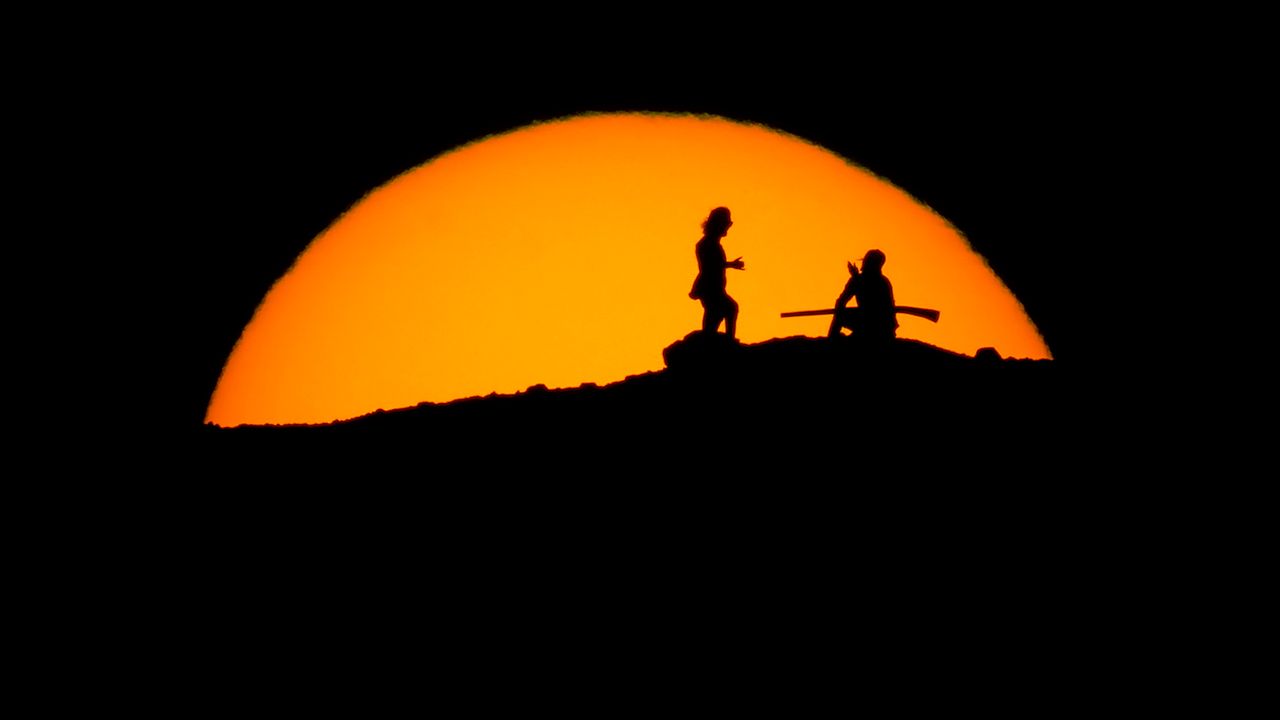 Hikers watch the sunset Saturday from a peak at Papago Park in Phoenix.