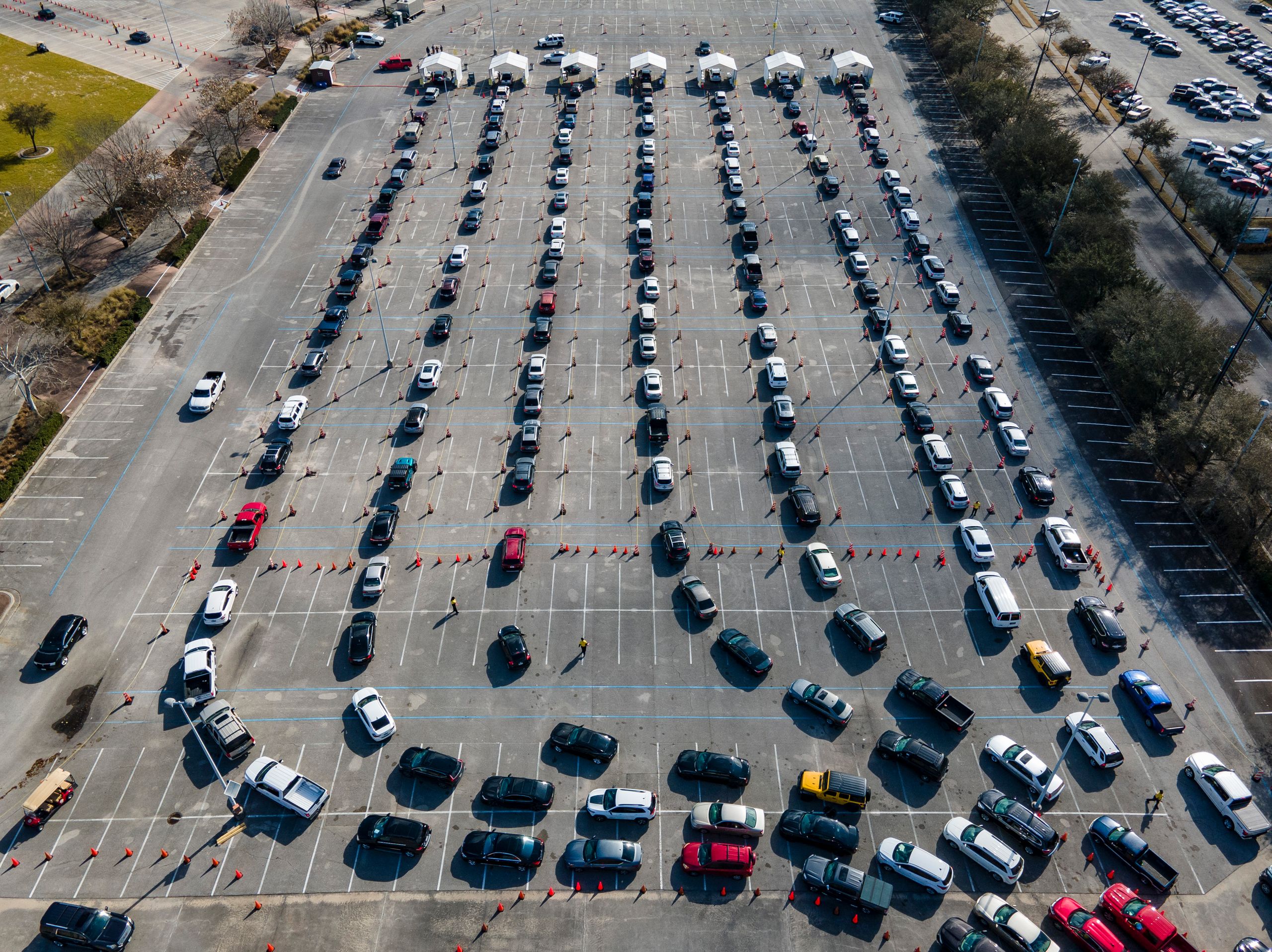 Cars line up in a parking lot at NRG Park in Houston as people wait to receive a COVID-19 vaccines at the federally supported