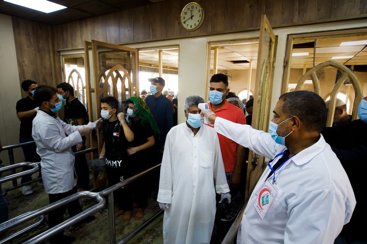 Health officials check temperatures as the faithful entering a mosque in Kufa, Iraq, on Sept. 11, 2020. 