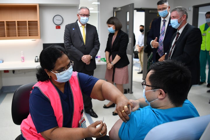 NSW Health Minister Brad Hazzard, left, and Premier Gladys Berejiklian look on Monday as NSW Health worker Andrew Santoso, a radiographer, receives his COVID-19 vaccination at Westmead Hospital.