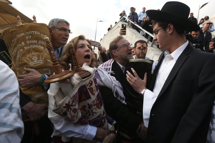 An ultra-Orthodox Jewish man tries to prevent Anat Hoffman (center), the founder and president of Women of the Wall, and members of the liberal group from entering the women's section of the Western Wall while carrying a Torah scroll in Jerusalem in November 2016 during a protest by the group demanding equal prayer rights at the site.