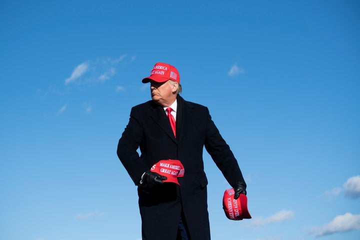 Trump, himself wearing a MAGA hat, throws some of them to his listeners at a rally for his reelection bid in Avoca, Pennsylvania on Nov. 2, 2020.